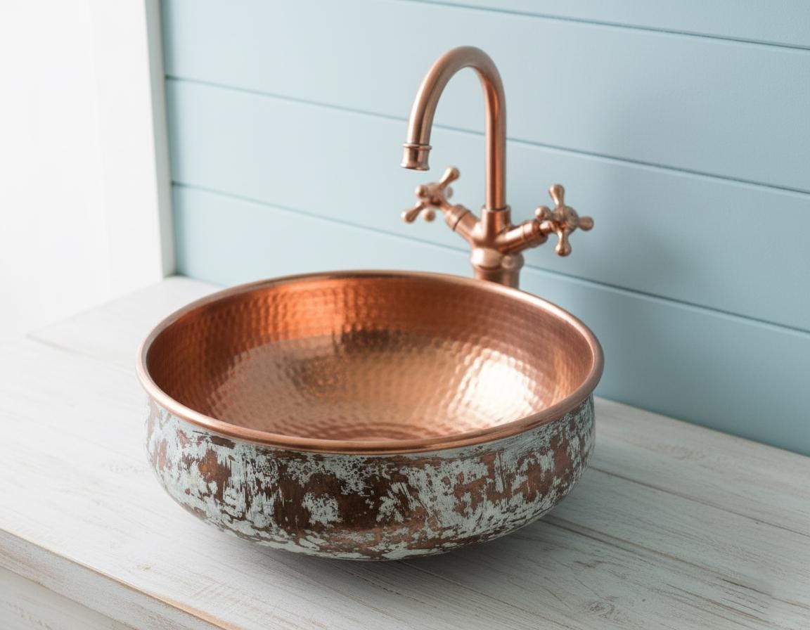 Copper sink with faucet on a light wooden surface against a light blue wall.