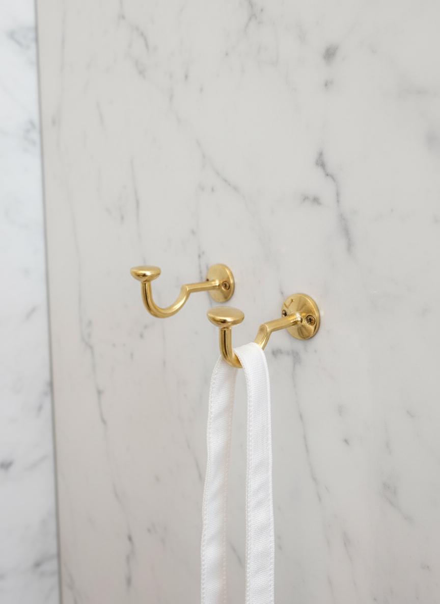 Gold towel hook with white towel on a marble wall