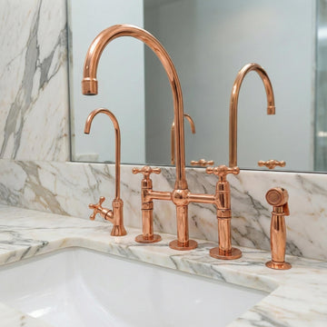 Copper kitchen faucet set on a marble countertop with a mirror in the background