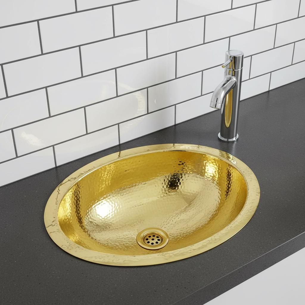 Gold sink on a black countertop with a white tiled wall background