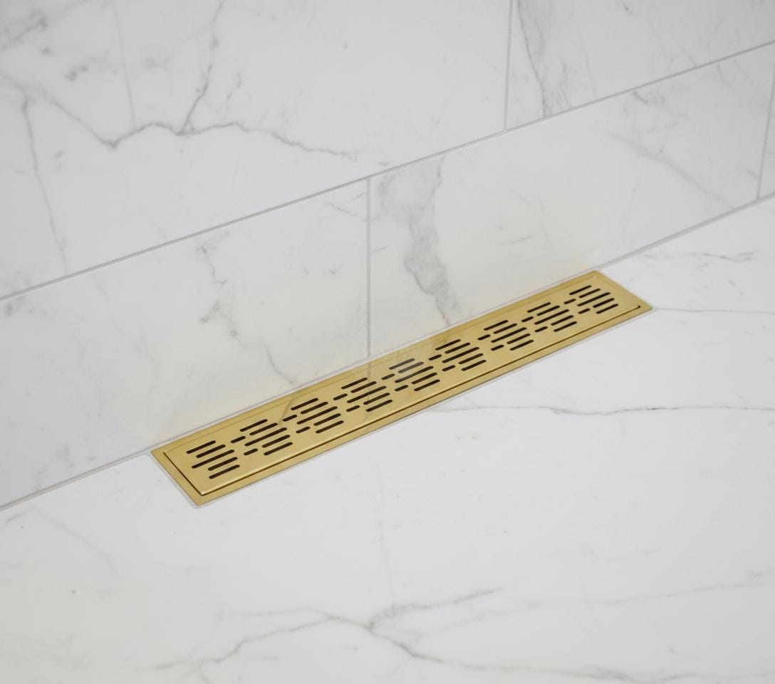 Gold rectangular floor drain cover on a marble floor