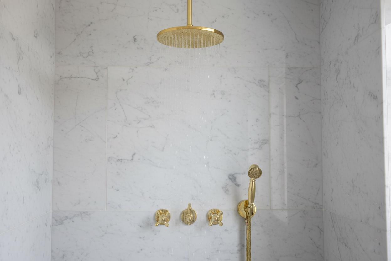Gold shower head and fixtures on a marble wall