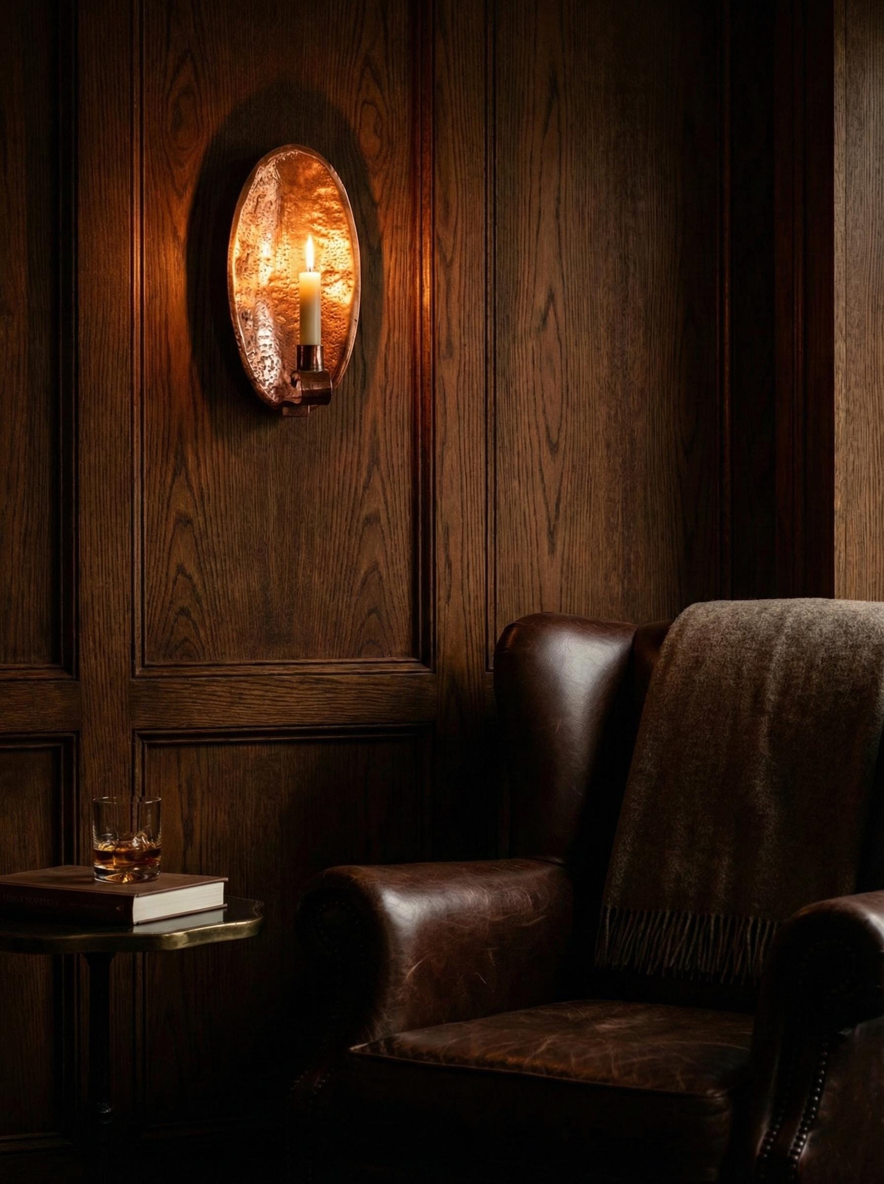 Cozy corner with a leather armchair, wooden wall paneling, and a round mirror.