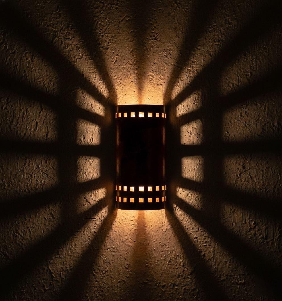 Wall-mounted light fixture casting shadows on a textured wall