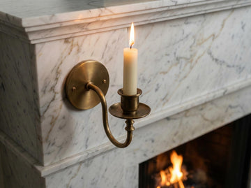 Candle in a brass wall sconce on a marble fireplace