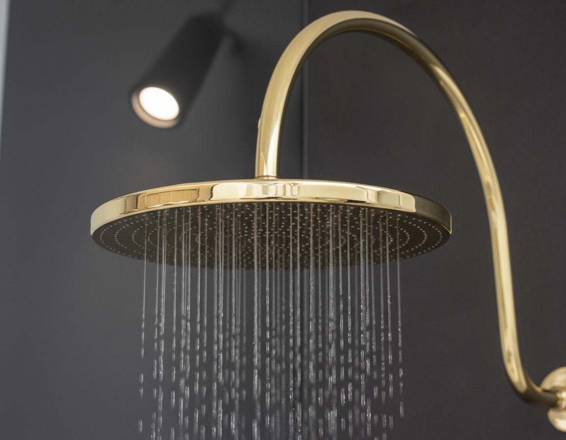 Gold shower head with water droplets against a dark background