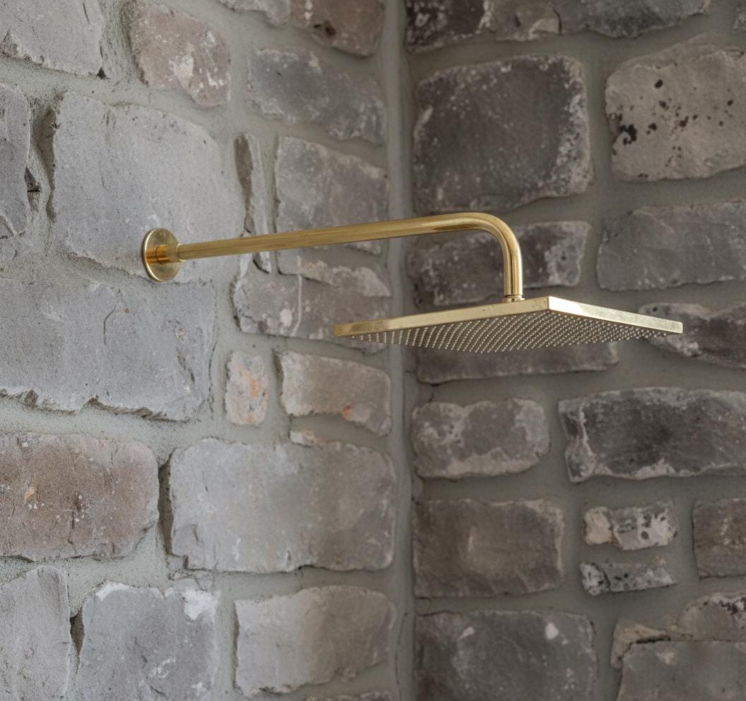 Gold shower head mounted on a stone wall