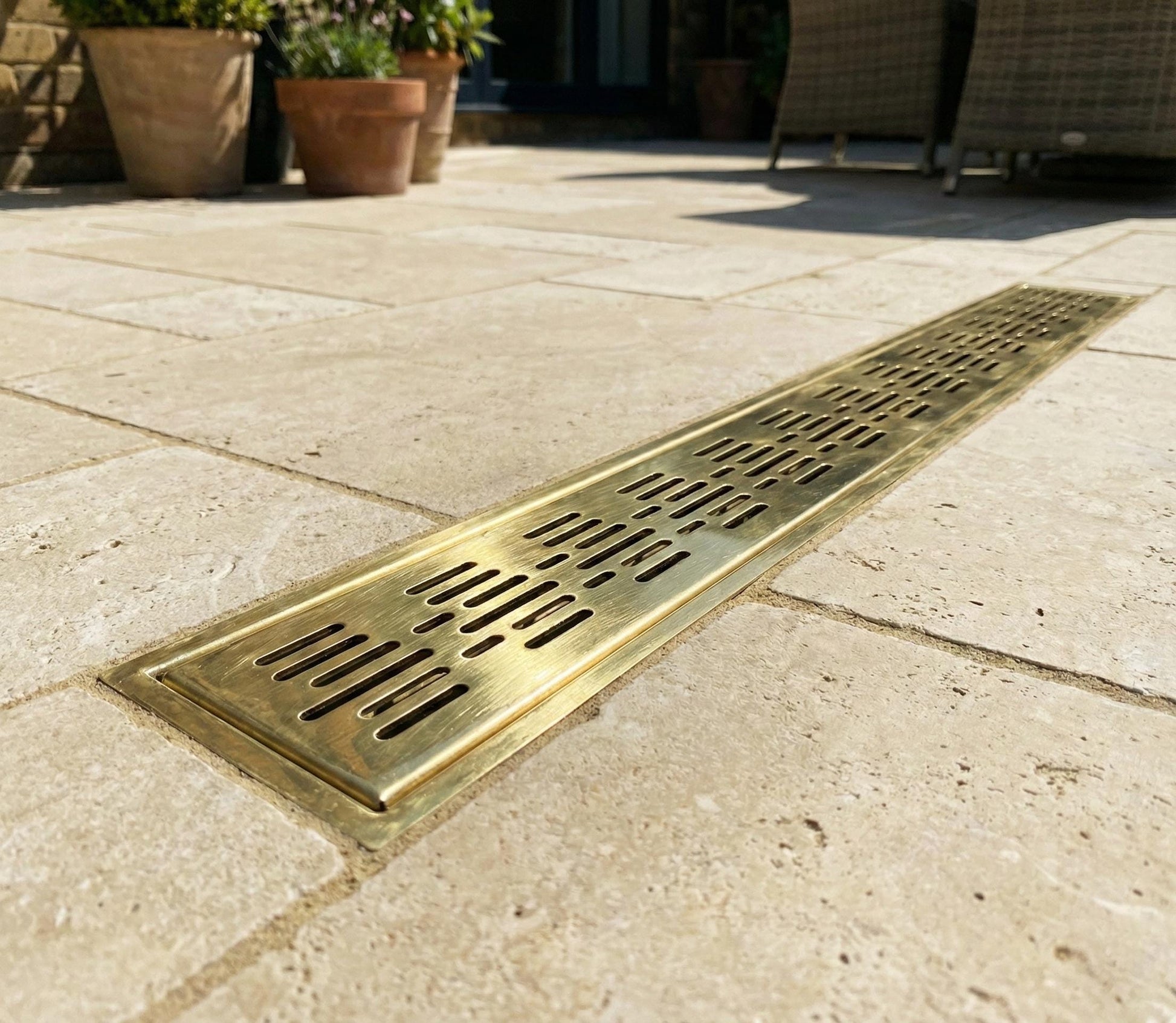 Long rectangular brass drain cover on a stone patio
