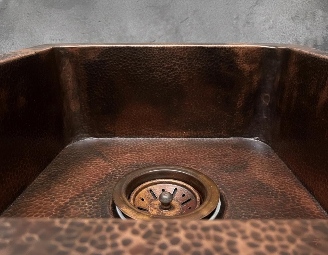 Close-up of a copper kitchen sink with a textured surface and drain.