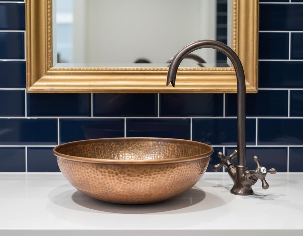 Copper sink with bronze faucet against a blue tiled wall