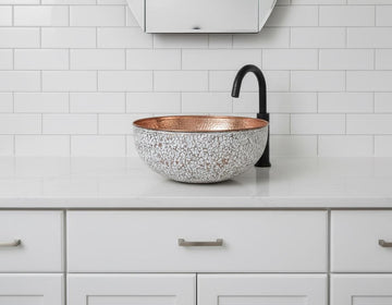 Copper sink on a white countertop with a tiled wall background