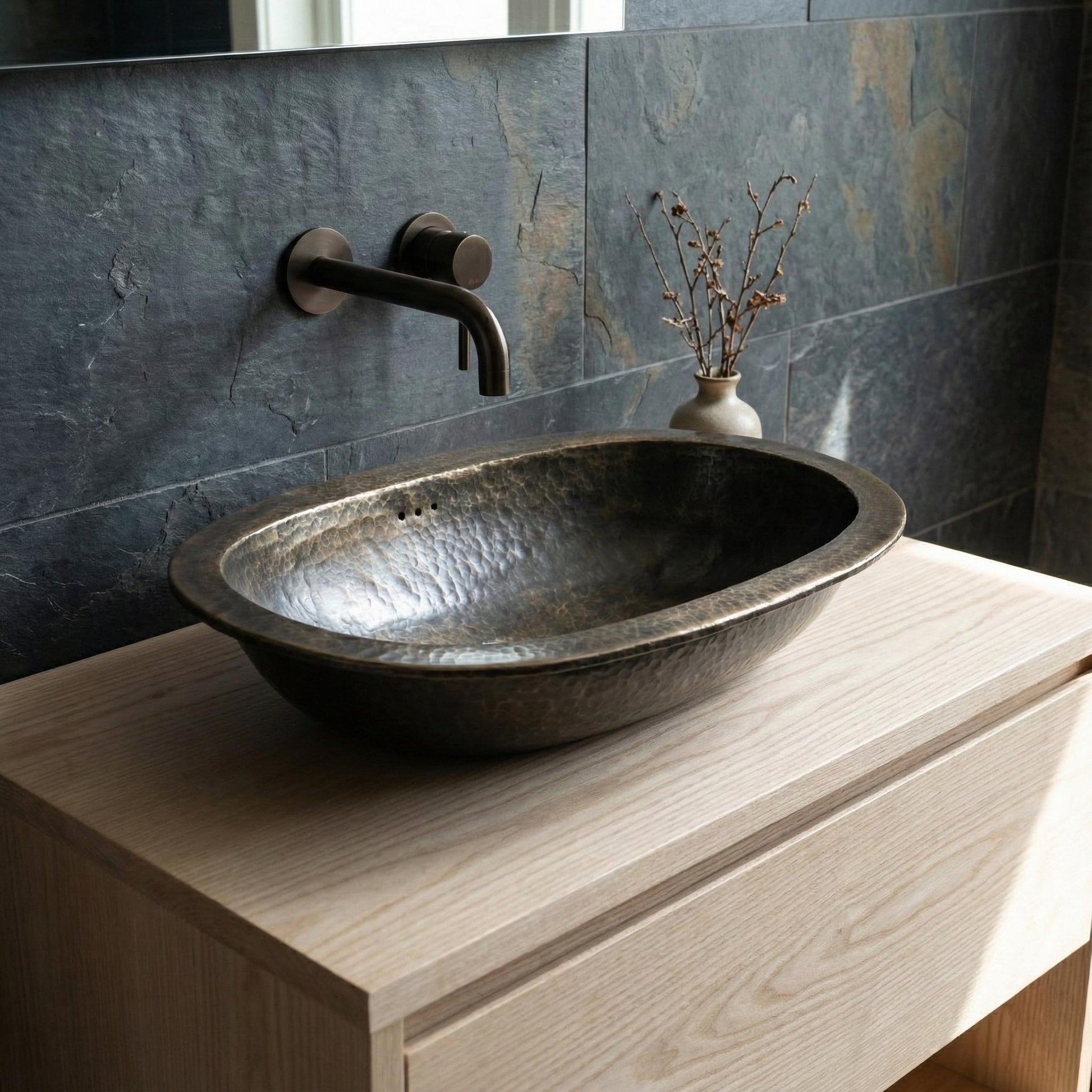Bathroom sink with metallic faucet against a stone wall