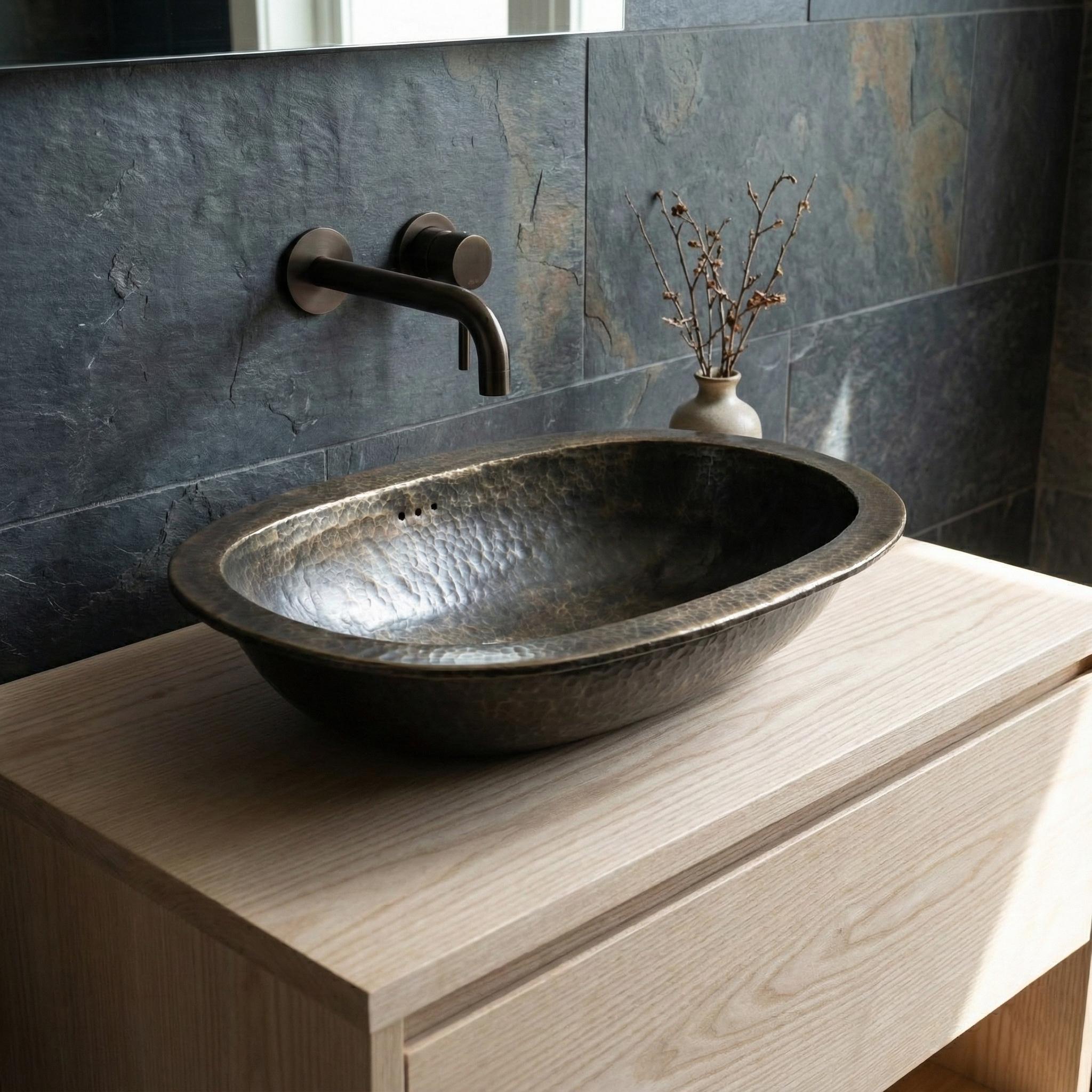 Bathroom sink with metallic faucet against a stone wall