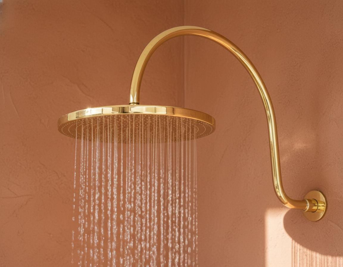 Gold shower head on a pink wall
