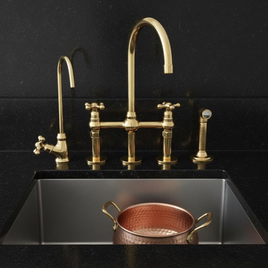 Gold faucet and handles on a black sink with a copper pot.
