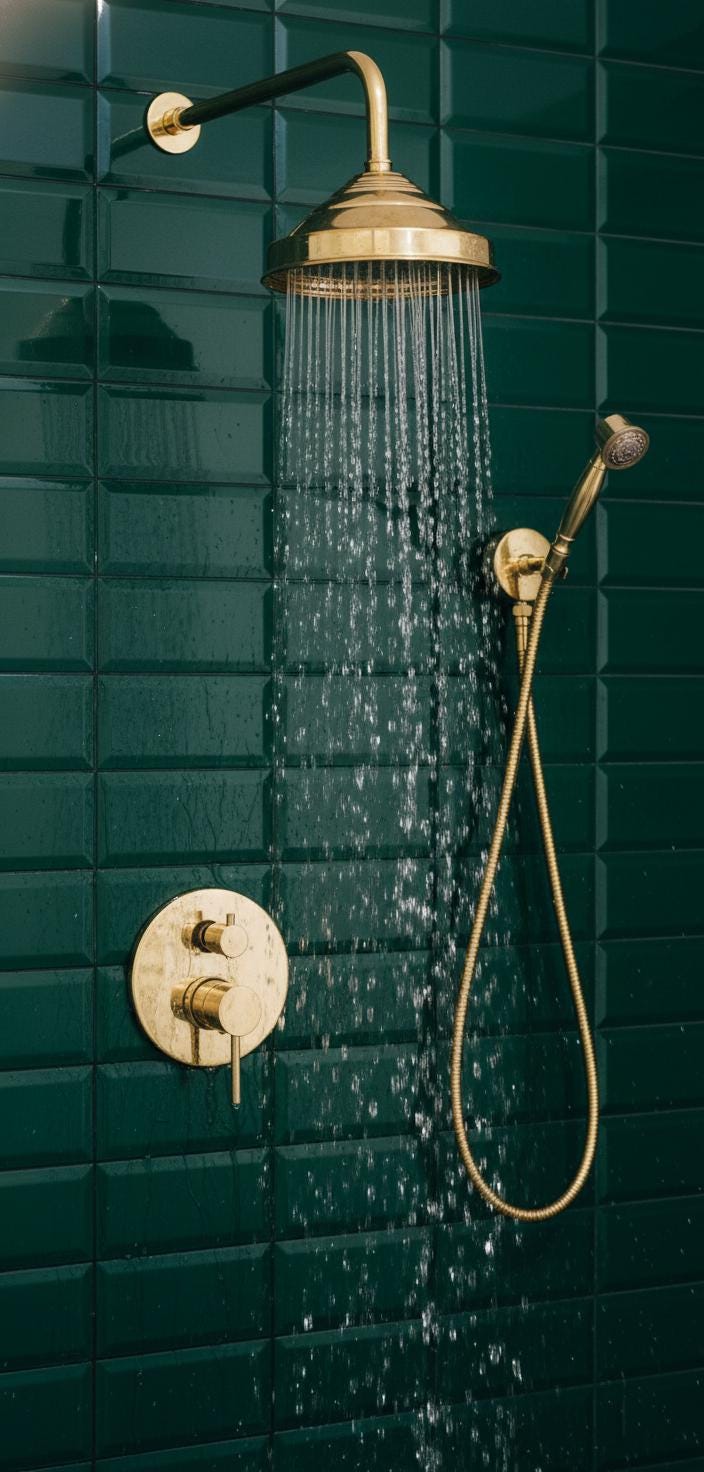 Gold shower head and control valve on a green tiled wall