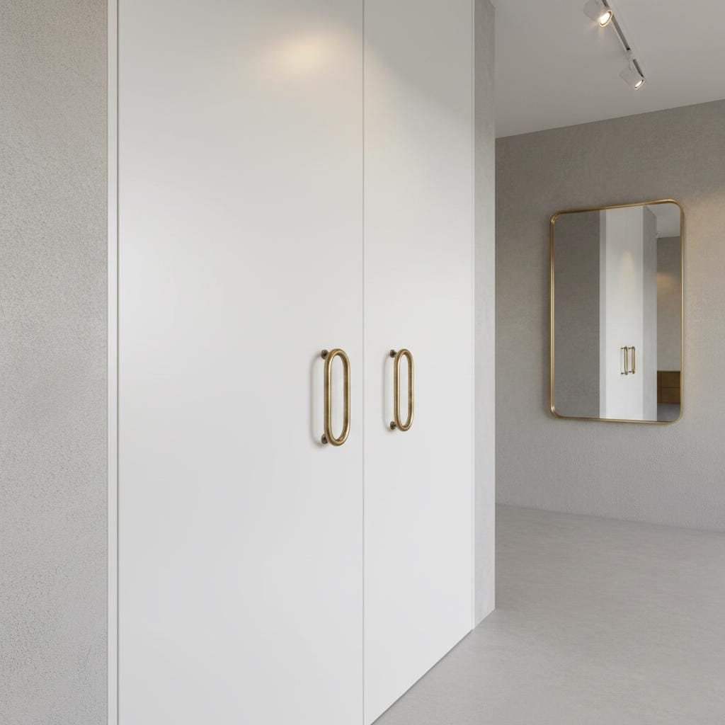 Modern interior with a white door featuring gold handles and a mirror on a gray wall.
