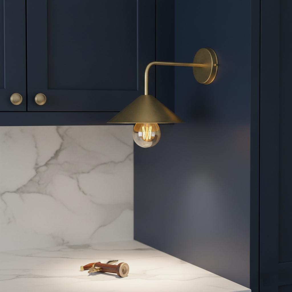 Gold wall-mounted lamp in a kitchen setting with blue cabinets and marble countertop.
