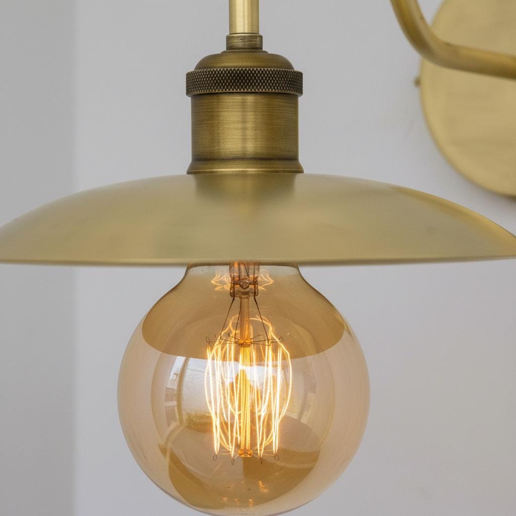 Gold pendant light with a visible bulb against a plain background