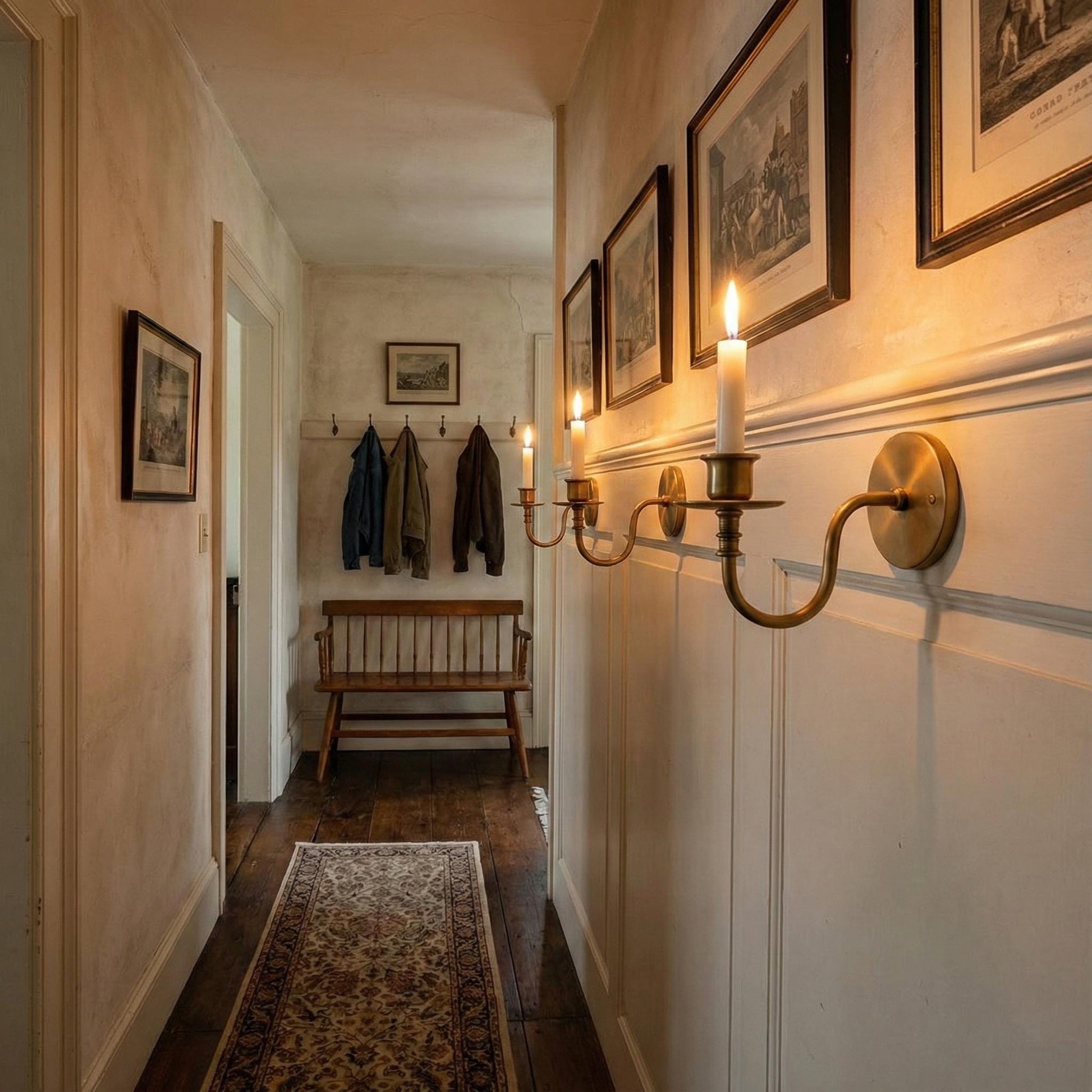 Narrow hallway with a wooden bench, hanging coats, and wall sconces.