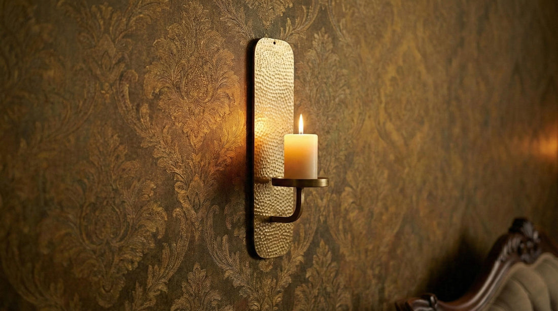 Cozy bedroom with a lit candle on a wall sconce, pillows on a bed, and a cup on a nightstand.