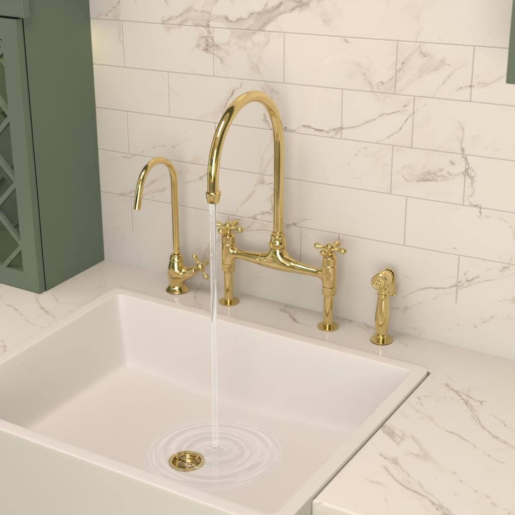Gold kitchen faucet set on a white sink with marble tiles in the background