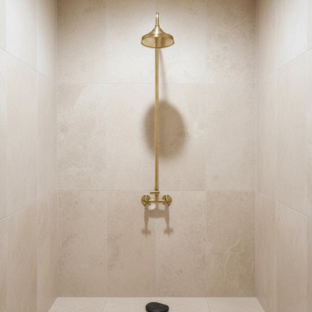 Gold shower head and control valve against a beige tiled wall