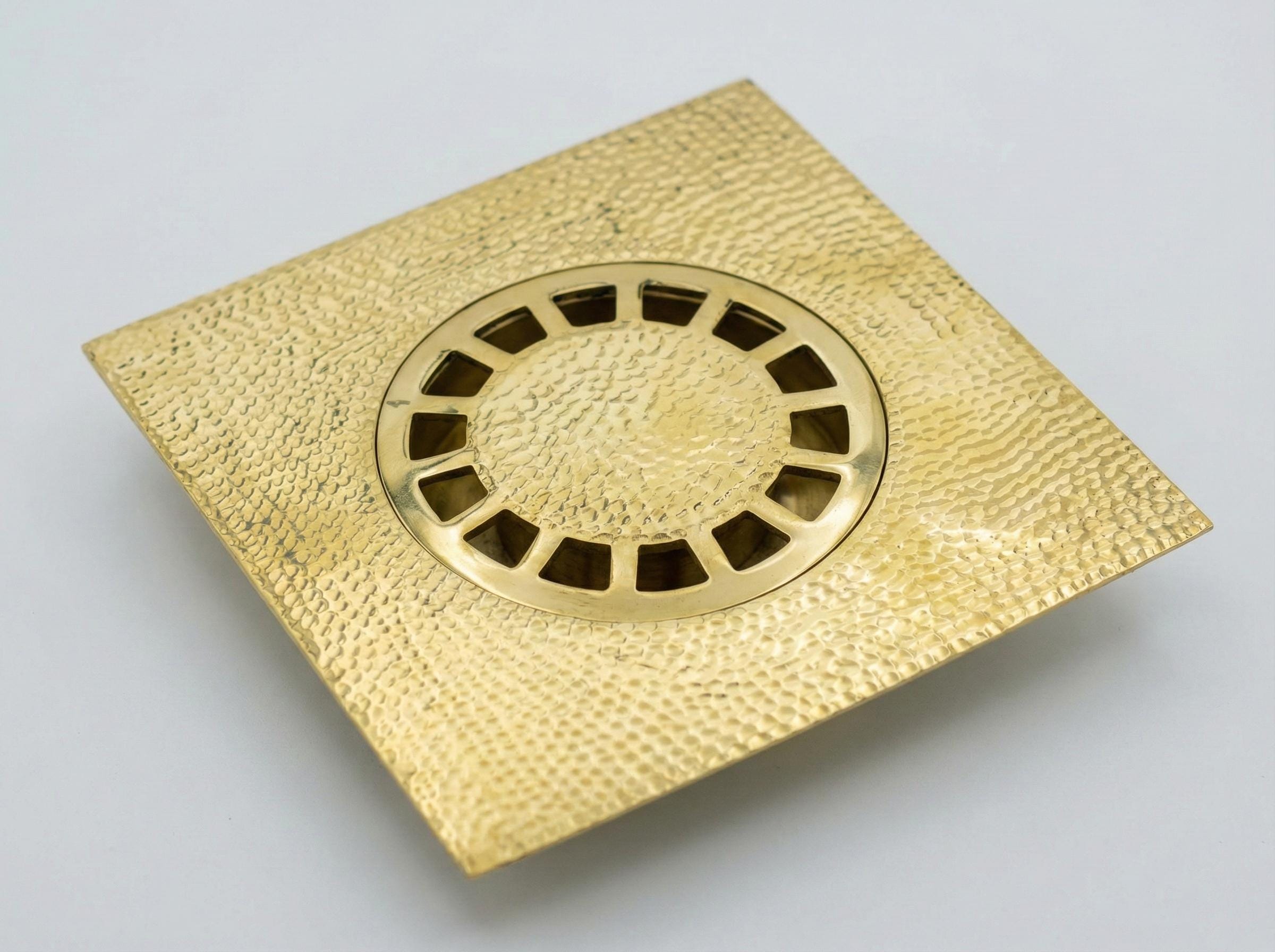 Gold-colored brass drain cover on a light gray background
