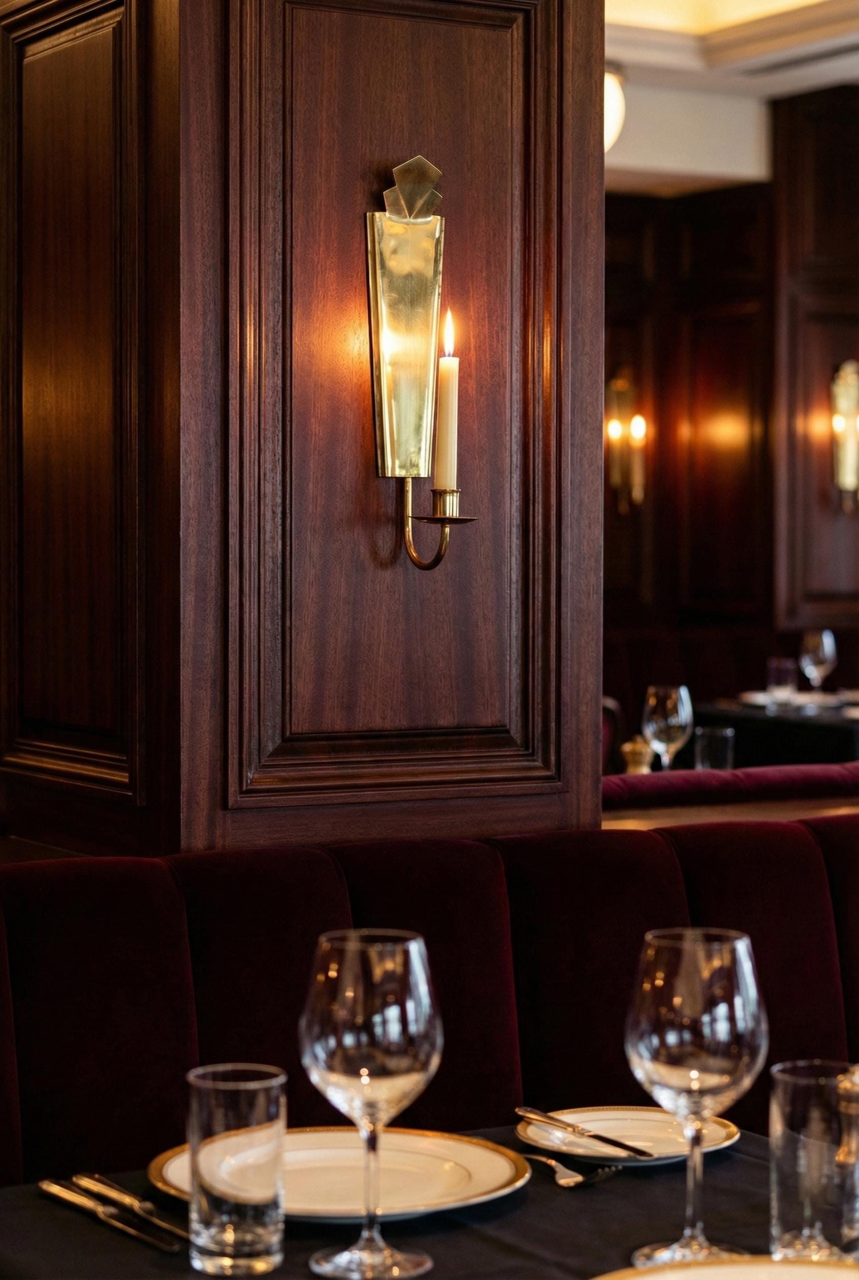Dining area with wooden wall paneling, candlelit wall sconce, and set tables.