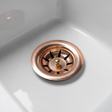 Copper sink drain stopper on a white sink background