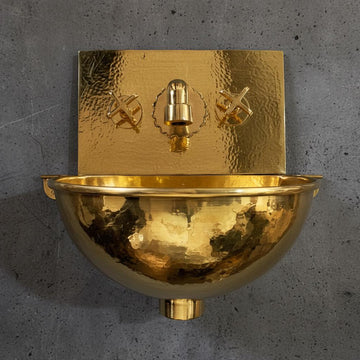 Gold wall-mounted sink with decorative design on a gray concrete background