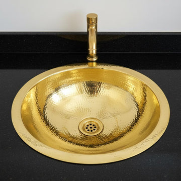 Gold sink with faucet on a black countertop