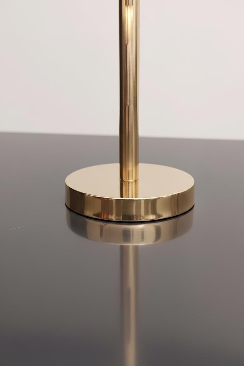 Gold lamp on a reflective surface with a plain background