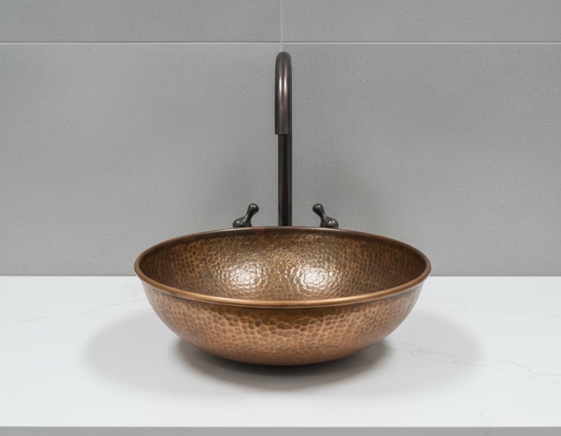 Bronze sink with a faucet against a gray tiled wall.