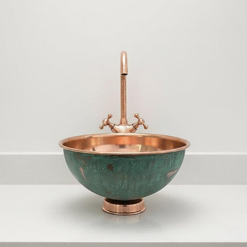 Copper sink with greenish-blue basin on a white surface and light gray background