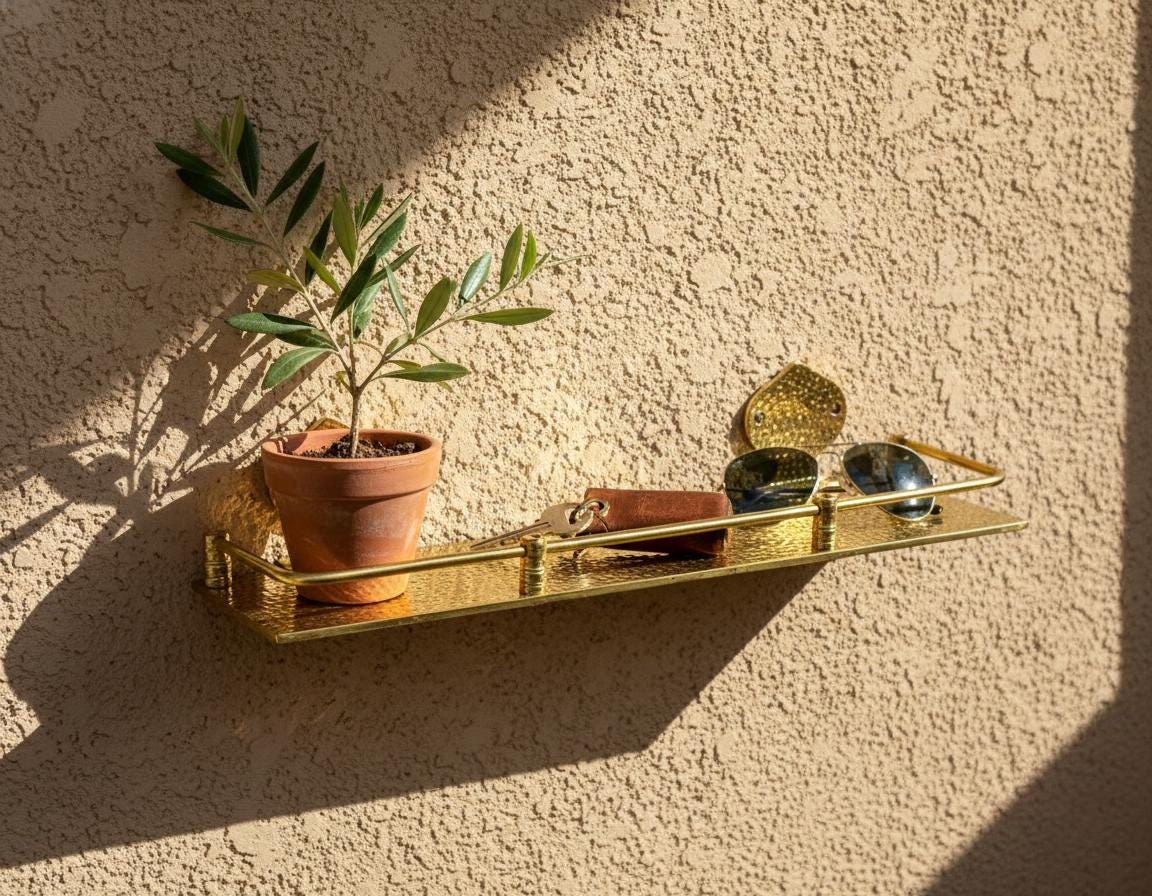 Gold shelf with a plant and decorative items against a textured wall.