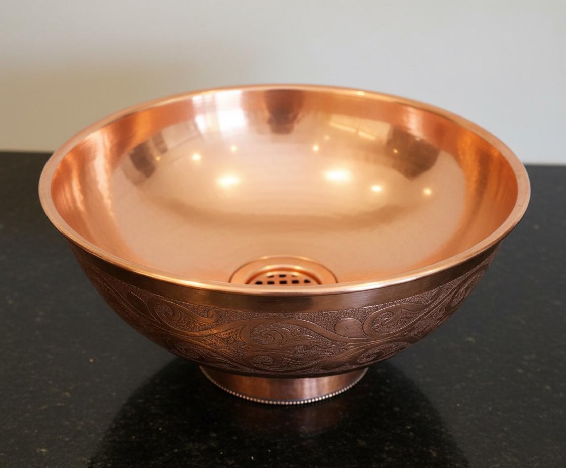 Copper bowl with embossed design on a black surface