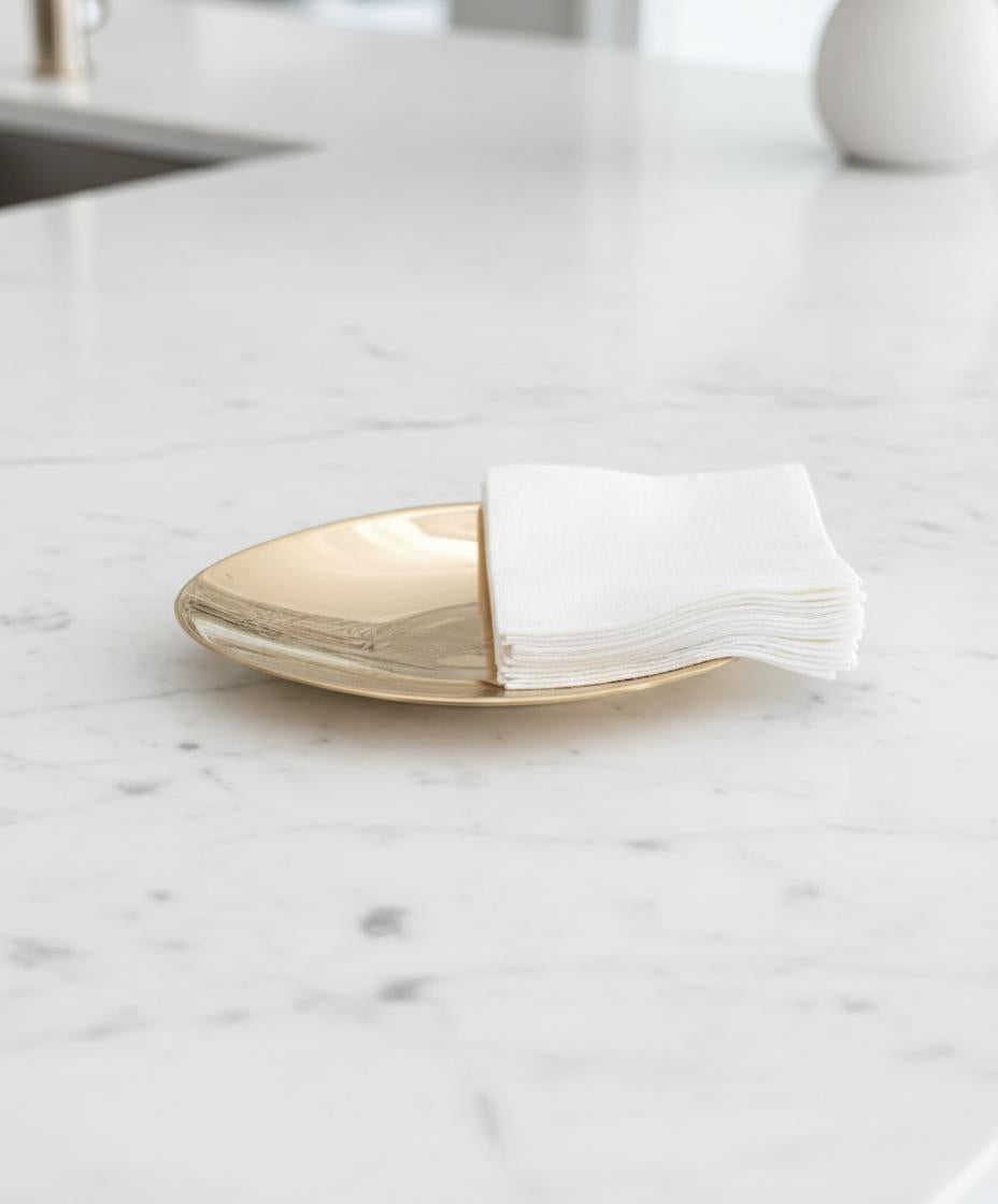 Gold plate with folded white napkin on a marble surface
