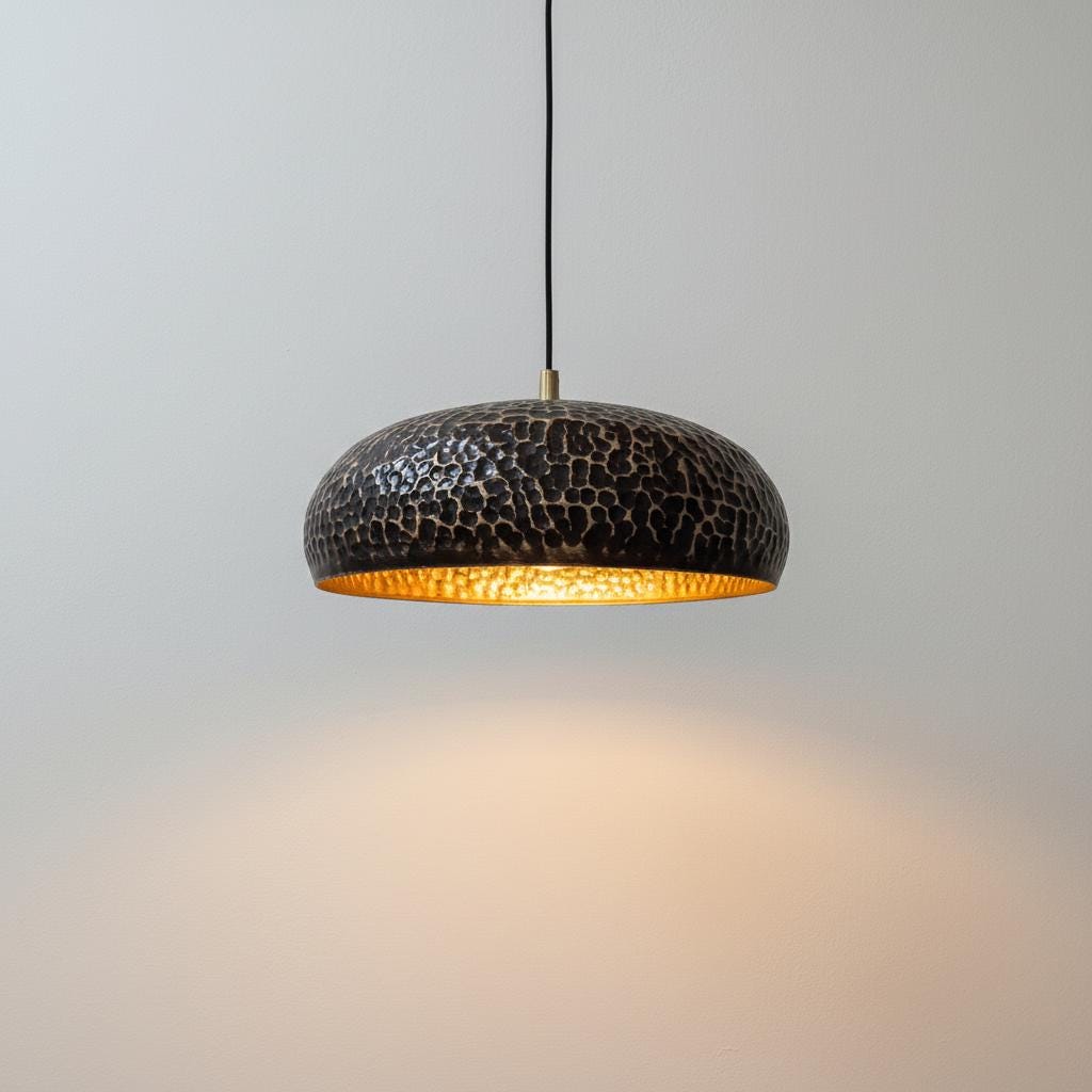 Pendant light with textured black shade and gold interior on a gray background