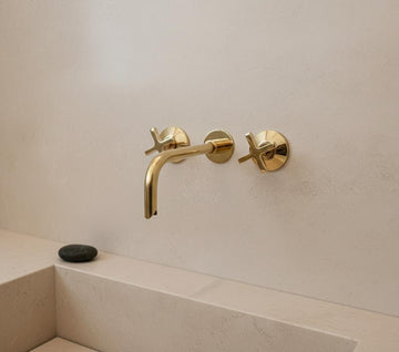 Gold faucet and handles on a white wall