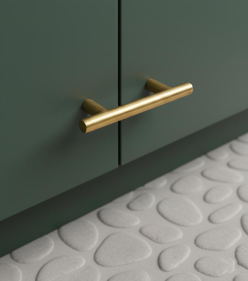 Gold cabinet handle on a green cabinet with a textured gray floor.