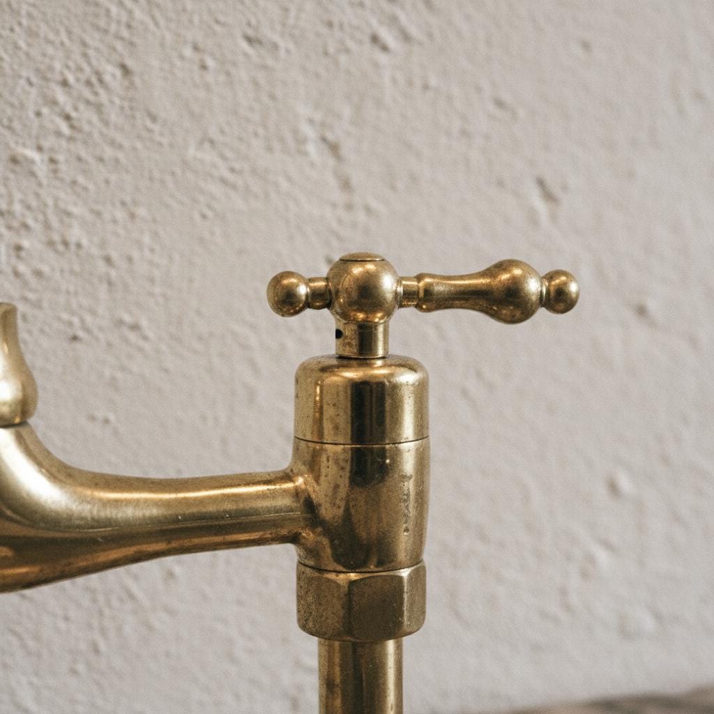 Close-up of a brass faucet against a textured wall.