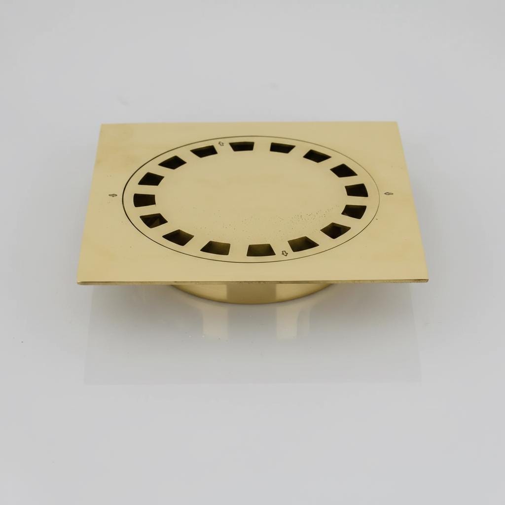 Gold-colored square floor drain cover on a white background