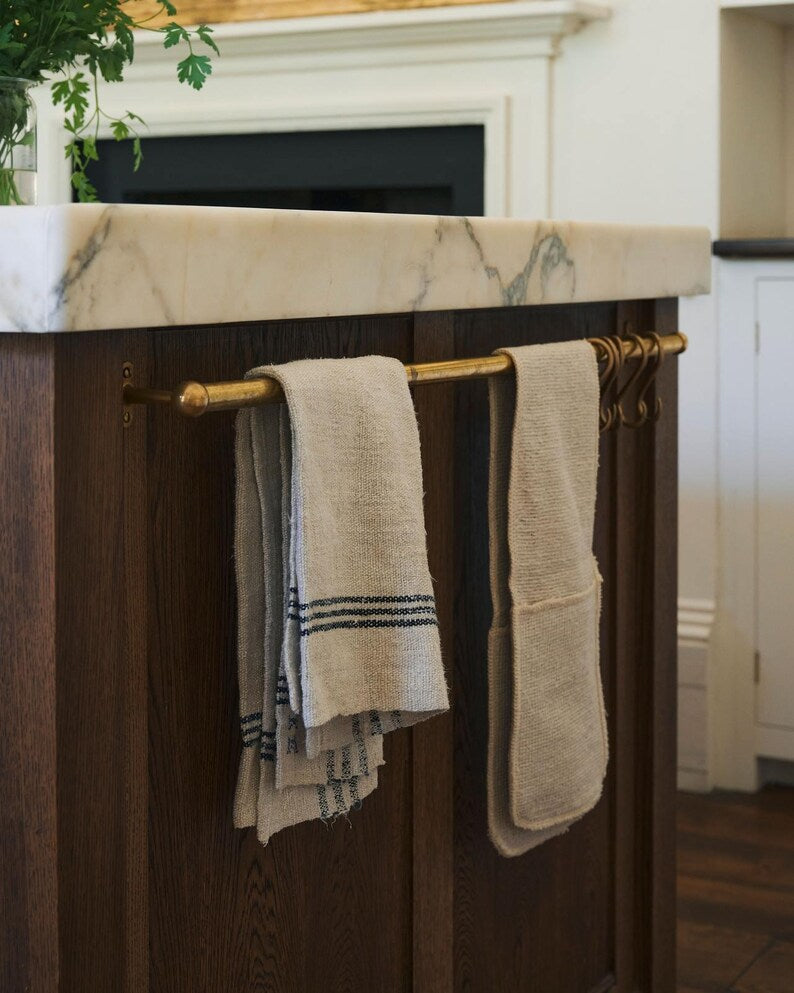 Moroccan unlacquered brass kitchen rail rack with hooks mounted on rustic white wall

