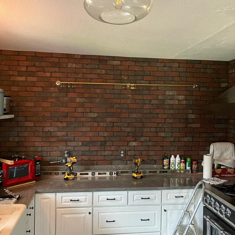 Moroccan unlacquered brass kitchen rail rack with hooks mounted on rustic white wall